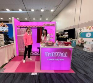 BelliWelli's 10x10 booth featuring checkered flooring and a Booth by Bryant photo booth at Natural Products Expo West 2025.