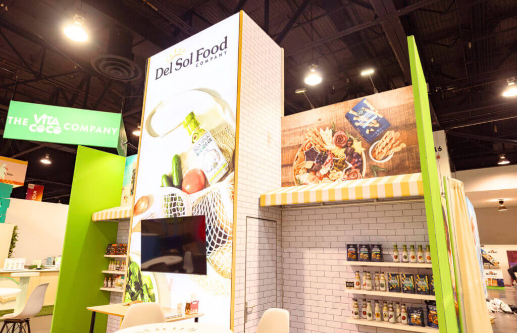 Del Sol Food Company trade show booth rental at Expo West with branded counters, backlit tower and product displays